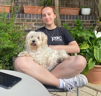 Photo of Toni sitting cross-legged with their dog Bella